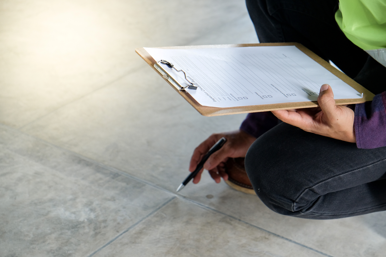 Man with clipboard inspecting floor