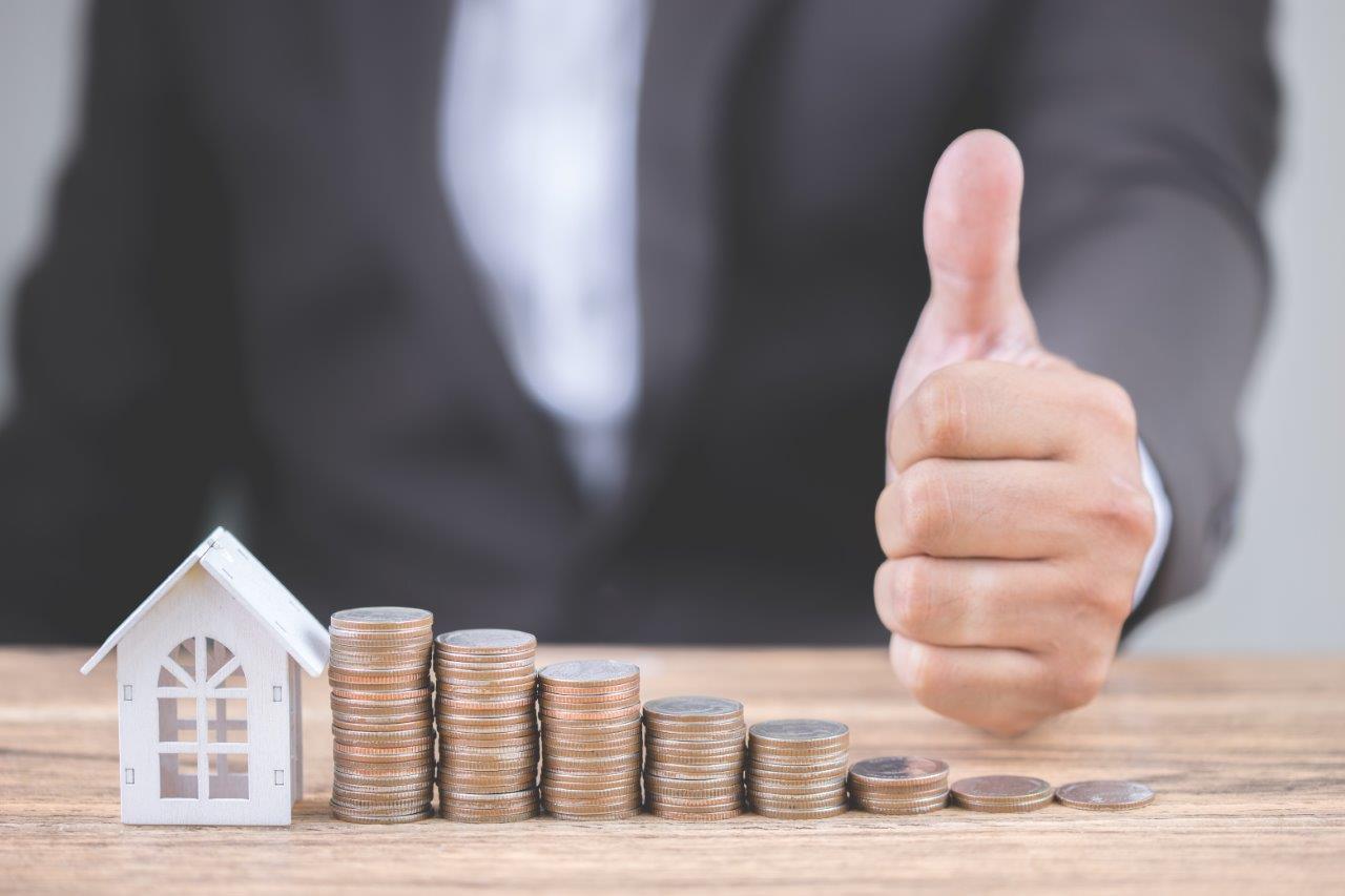 man giving thumbs up in front of stack of coins