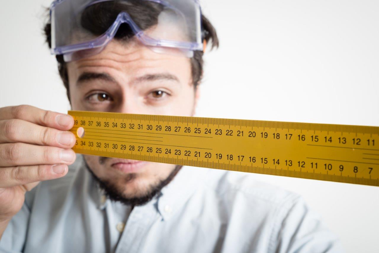 man looking down a ruler