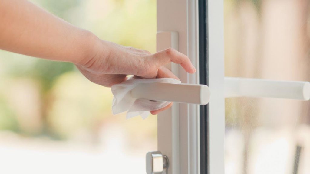 woman disinfecting door handle