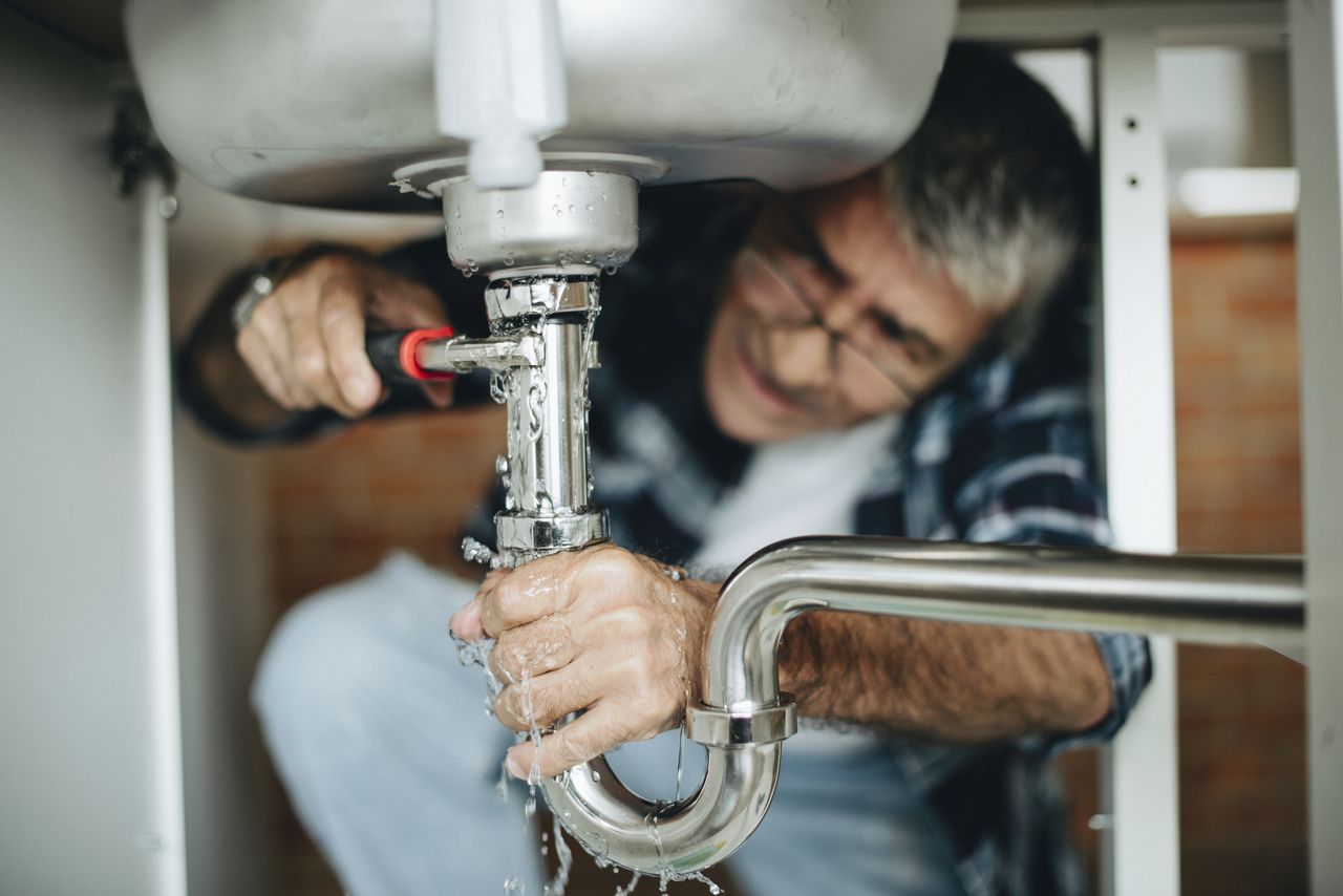 A man fixing his leaky sink