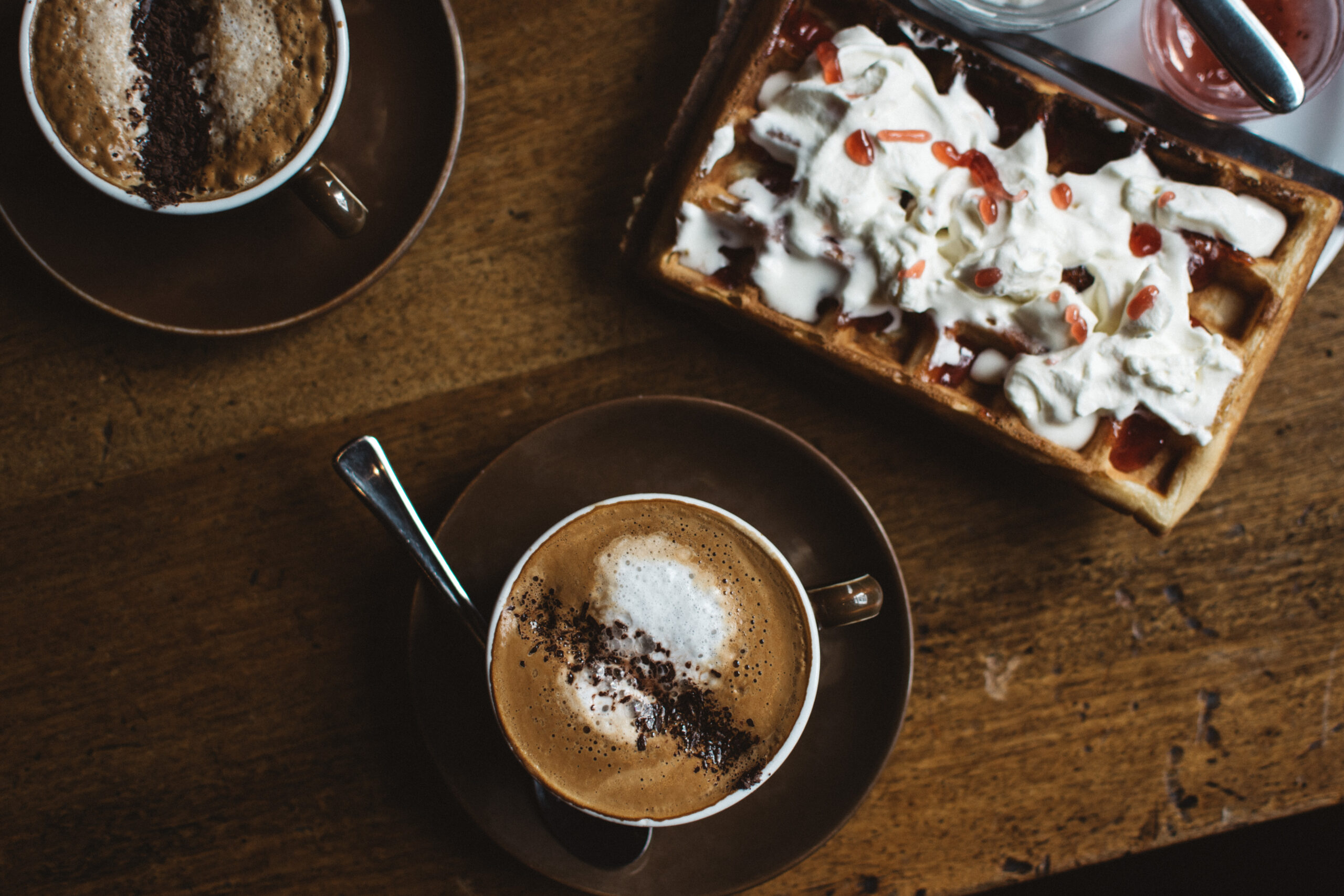 Wooden desk with two cappuccinos and waffle