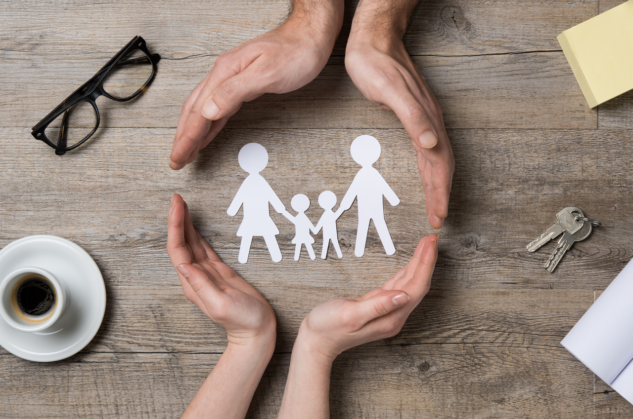 Close up of female and male hands protecting a paper chain family